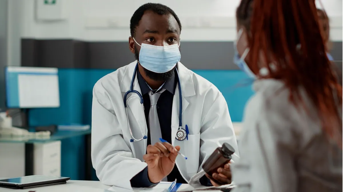 Un médecin en consultation présente une boîte de médicaments à une patiente