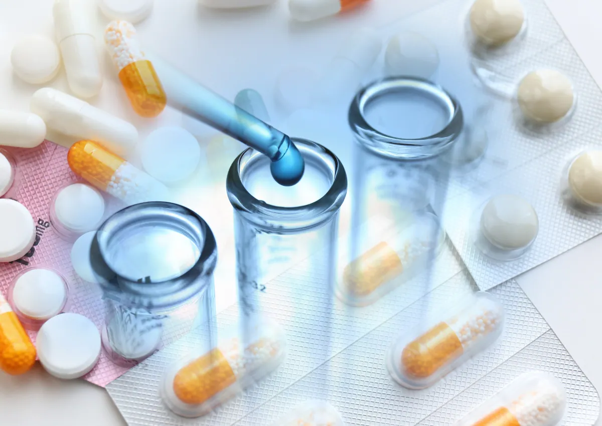 Capsules, comprimés et flacons de laboratoire, une pipette au-dessus d'un tube à essai